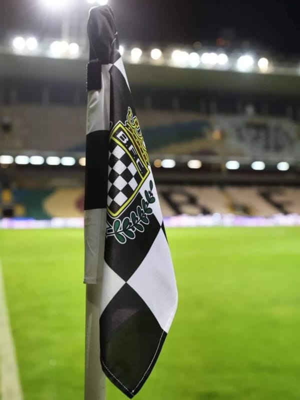 Bandeirola de canto com o emblema do Boavista FC, no Estádio do Bessa vazio, à noite.